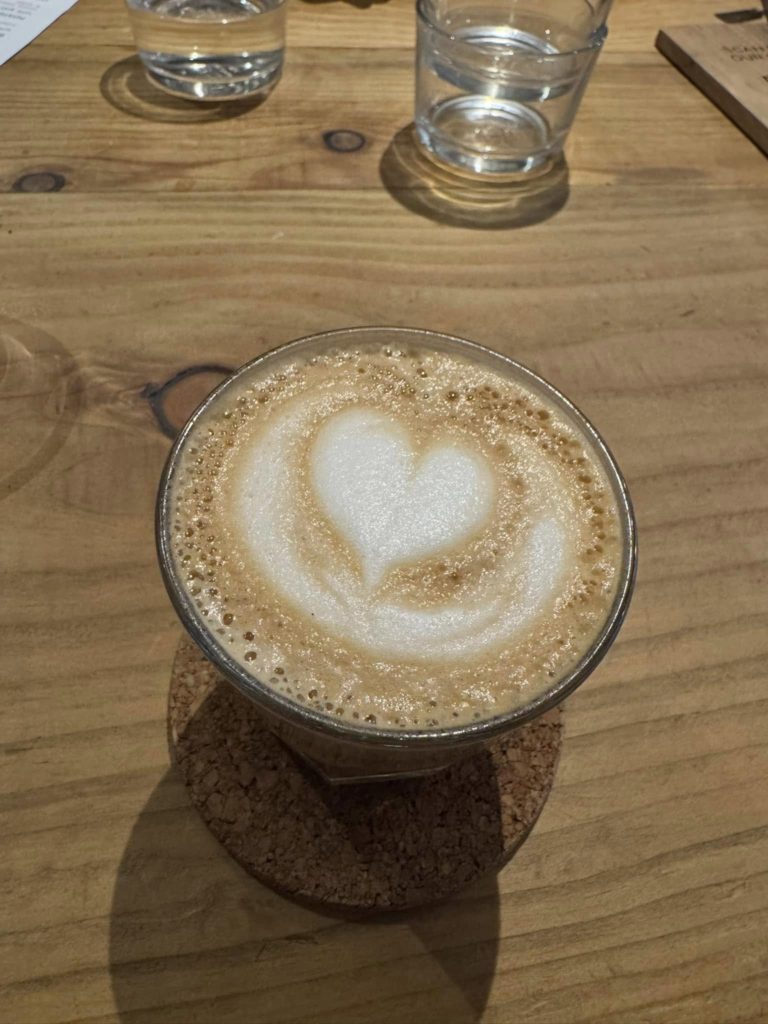 A flat white coffee with a latte art heart on the top of the drink.